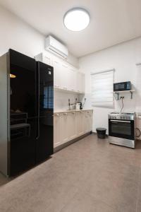 eine Küche mit weißen Schränken und einem schwarzen Kühlschrank in der Unterkunft O&O Group - Stunning Chic 2 BR Ibn Gvirol St in Tel Aviv