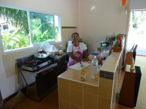 una mujer parada en una cocina preparando comida en Khao Sok Jasmine Garden Resort - SHA Certified, en Khao Sok