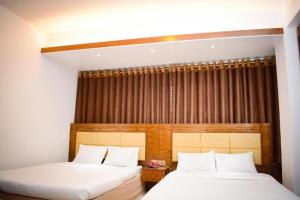 a bedroom with two beds and a window at The Alina Hotel & Suites in Chittagong