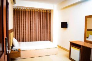 a small bedroom with a bed and a curtain at The Alina Hotel & Suites in Chittagong