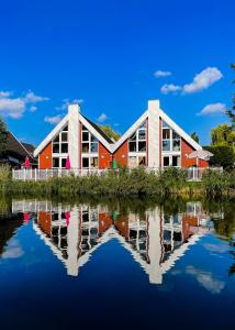 un edificio rojo con un reflejo en el agua en Ferienhaus mit Wasserterrasse - mit Sauna und Kamin - inklusive Nebenkosten, en Wendisch Rietz