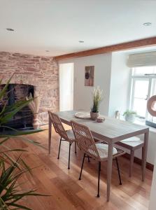 a dining room with a table and chairs and a fireplace at Seapink, Kingsand; luxury Cornish cottage with seaviews, bbq & paddleboards in Kingsand