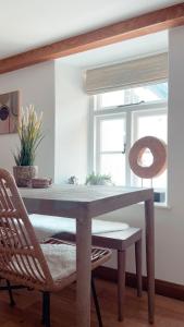 a wooden table with a chair and a window at Seapink, Kingsand; luxury Cornish cottage with seaviews, bbq & paddleboards in Kingsand