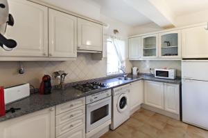 a kitchen with white cabinets and a stove top oven at Cabanas Village in Cabanas de Tavira