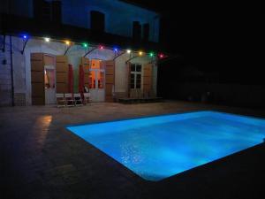 a swimming pool at night with lights on a building at A la Gare in Saint-Nexans
