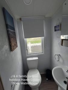 a bathroom with a white toilet and a window at J&A Family Caravan Haven Mablethorpe in Mablethorpe