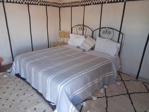Couleur du désert في Mhamid: غرفة نوم بسرير كبير عليها شراشف ووسائد بيضاء