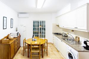 a kitchen with a wooden table and a kitchen with white cabinets at Cabanas Vintage Apartment in Tavira