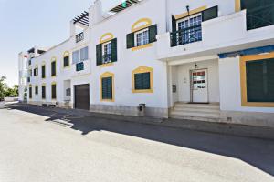 a white building with yellow and green shuttered windows at Cabanas Vintage Apartment in Tavira