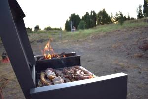 a grill with meat and fire in a field at Las Loicas B&B in Esquel