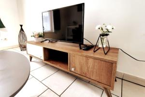 a television on a wooden entertainment center in a living room at Logement entier proche tribunaux in Douai