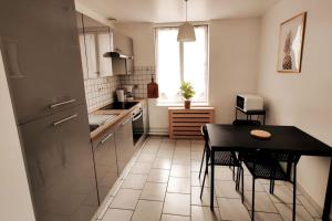 a kitchen with a black table and chairs in it at Logement entier proche tribunaux in Douai