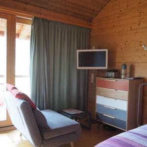 a bedroom with a bed and a chair and a television at Studio Raccard Cendré in Grône