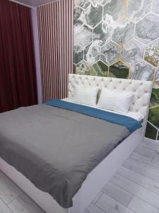 a large bed with a white headboard in a bedroom at Sezim Qala 10 in Taldykolʼ