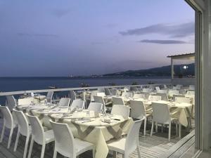 un grupo de mesas y sillas blancas en una cubierta en Belle vie luxury house, en Montepaone