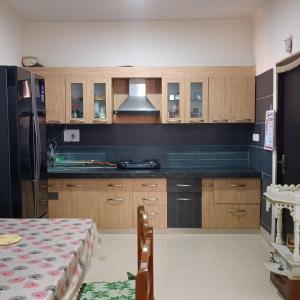 a kitchen with wooden cabinets and a table and a stove at Sunspot -Entire Villa Apartment in Ujjain
