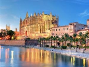 a large cathedral with palm trees in front of a river at Sant Francesc Hotel Singular in Palma de Mallorca