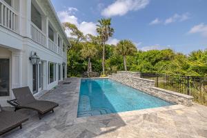a swimming pool with two chairs next to a house at JEKYLL HOUSE home in Jekyll Island