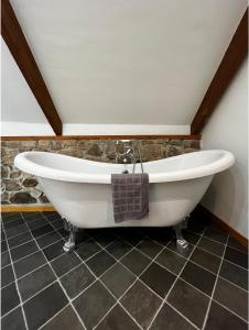 a bath tub in a bathroom with a stone wall at L'Annexe in Maël-Pestivien