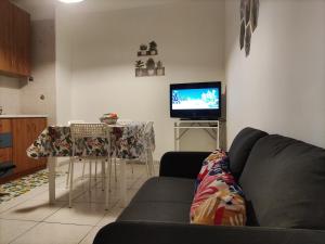sala de estar con sofá, mesa y TV en La Dimora Fiorita, en Catania