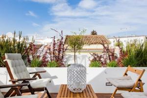 a patio with two chairs and a vase on a table at Casa Alecrim in Tavira