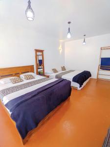 three beds in a room with orange floors and lights at White Home in Haputale