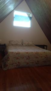 a bedroom with a bed with a window in a attic at Chalé no morro in Ubatuba