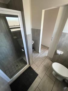 uma casa de banho com um chuveiro e um WC. em Ecomotel Louis Botha em Joanesburgo