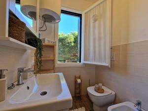 a bathroom with a sink and a toilet and a window at 650 metri dal Mare - WiFi - Terrazzo - Piscina - A/C in Pietra Ligure
