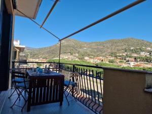 a table and chairs on a balcony with a view at 650 metri dal Mare - WiFi - Terrazzo - Piscina - A/C in Pietra Ligure