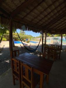 a table with chairs and a hammock on a beach at Pousada Trilha das Dunas in Jericoacoara
