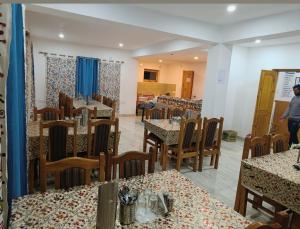 a restaurant with tables and chairs and a person in the background at Hotel Malik Residency in Leh