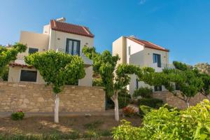 a house with trees in front of a stone wall at Vidakis Villas 4 in Sívas