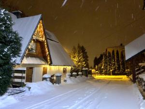 a church covered in snow at night with christmas lights at Ośrodek Sportowo-Rekreacyjny Słoneczny in Mszana Dolna