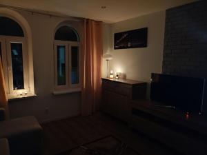 a dark living room with a tv and a window at Apartament Lago in Mrągowo