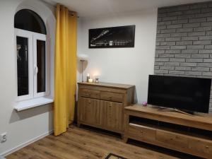 a living room with a flat screen tv on a wooden cabinet at Apartament Lago in Mrągowo