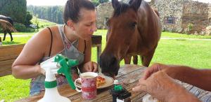 a woman eating food at a table with a horse at Aloe Inn Guest Farm in Piet Retief