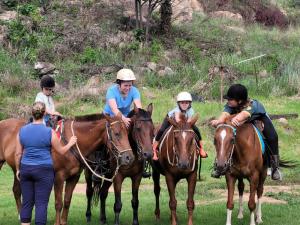 a group of people riding horses in a field at Aloe Inn Guest Farm in Piet Retief