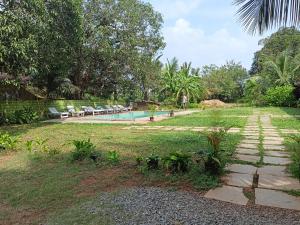 um jardim com piscina e algumas cadeiras e árvores em Luxury 6 BHK Villa with Private Swimming Pool em Old Goa