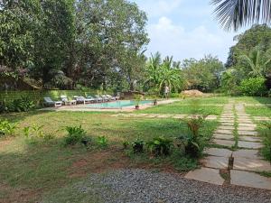 un giardino con piscina e alcuni alberi e sedie di Luxury 6 BHK Villa with Private Swimming Pool a Goa Velha