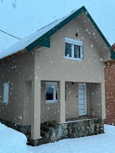 une maison recouverte de neige dans la cour dans l'établissement Apartman Kruna, à Kolašin