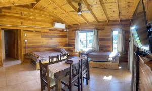 Cabaña de madera con mesa de comedor y sala de estar en Complejo Anthea en Villa Yacanto