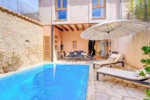 a villa with a swimming pool and an umbrella at Can Bodequita in Binissalem