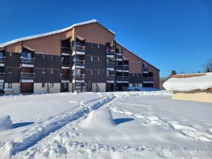 a snow covered parking lot in front of a building at LE CHALET, Superbe Duplex avec Balcon aux Rousses, Netflix, WI-FI, Parking Gratuit et Draps inclus - Animaux Interdits in Les Rousses