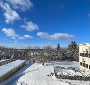 un patio cubierto de nieve con un edificio y un banco en Appart. lumineux pour 4pers. avec piscine chauffée, en Saint-Laurent-du-Jura