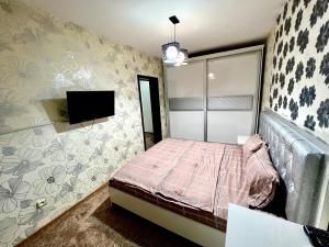 een slaapkamer met een bed en een tv aan de muur bij Flagman apartment в центре города in Tasjkent