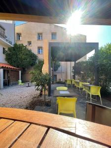 eine Terrasse mit Tischen und gelben Stühlen und ein Gebäude in der Unterkunft Résidence du Soleil in Collioure