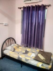 a bed in a room with a purple curtain at Beaufort Paguyut Homestay in Beaufort