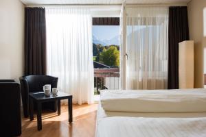 Schlafzimmer mit einem Bett, einem Tisch und einem Fenster in der Unterkunft Jungfrau Hotel Annex Alpine-Inn in Wilderswil