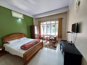 a bedroom with a bed and a desk and a television at Odyssey Stays Jowai - West Jaintia Hills in Jowai
